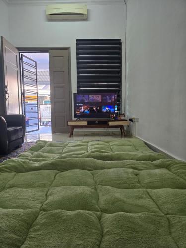 a large green bed in a room with a television at NEEK TOMS HOMESTAY MELAKA Near UITM Lendu - MRSM ALOR GAJAH- ENTER EXIT VIA LEBUH AMJ- SELF CHECK-IN in Kampong Alor Gajah