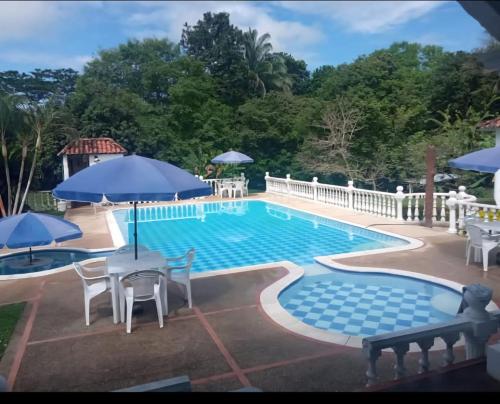 a swimming pool with tables and chairs and umbrellas at Catedral mx in Melgar