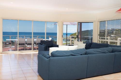 a blue couch in a living room with a view of the ocean at Palm Road in Forster