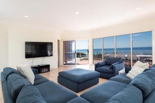 a living room with a blue couch and a television at Palm Road in Forster