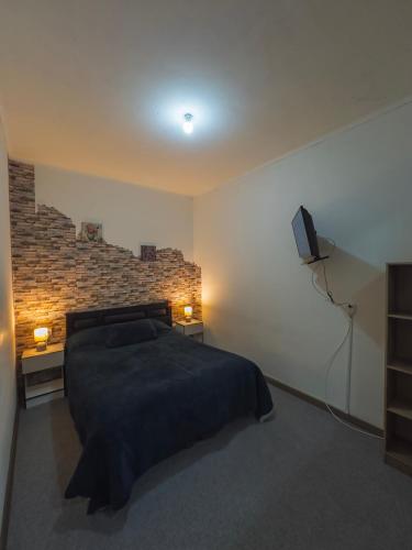 a bedroom with a bed and a tv on the wall at Hostal Antonella in Los Ángeles