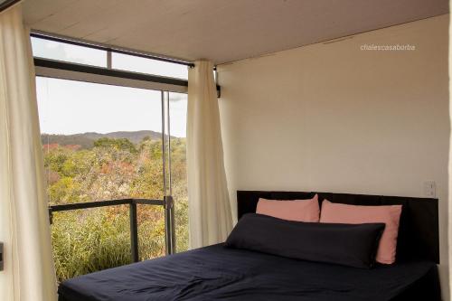 a bedroom with a bed and a large window at Casa Borba Chalé com piscina in Alto Paraíso de Goiás