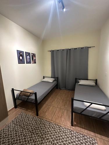 a room with two beds and a rug at Pousada Araquari in Paraty