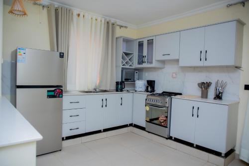a kitchen with white cabinets and a refrigerator at A Beautiful home, Kanombe, Nyarugunga in Kigali