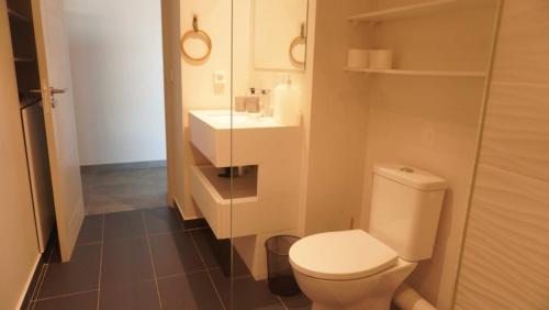 a bathroom with a white toilet and a sink at TAHITI - Sky M Appartement in Faaa