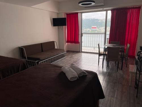 a bedroom with a bed and a living room with a table at Hermosa Suite Torres Gemelas in Acapulco