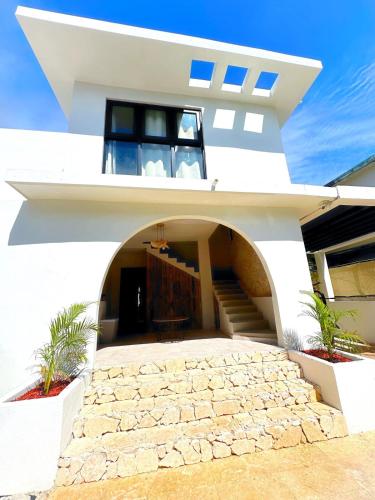 a white house with an archway and stairs at Unique Villa with private pool in Mayaguez in Mayaguez