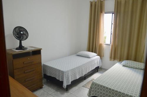 a bedroom with two beds and a dresser and a window at Apto 2 dormitórios 1 banheiro 1 vaga descoberta in Piracicaba