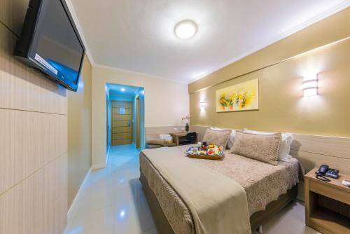a hotel room with a bed and a flat screen tv at Hotel Thomasi Express - Londrina in Londrina