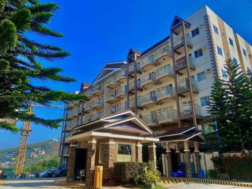 Un gran edificio blanco con árboles delante. en JAZZCOZY Condo Unit na SWAK SA BUDGET, en Baguio