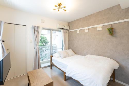 a bedroom with a white bed and a window at Maxim 2-B in Naha