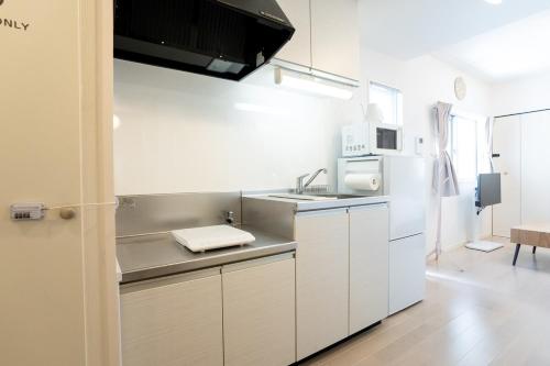 Una cocina blanca con fregadero y refrigerador. en Maxim 2-B, en Naha