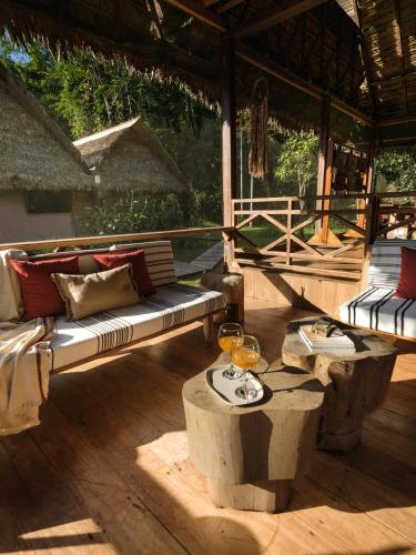 a patio with a couch and a table with wine glasses at Explorers Inn in Tambopata