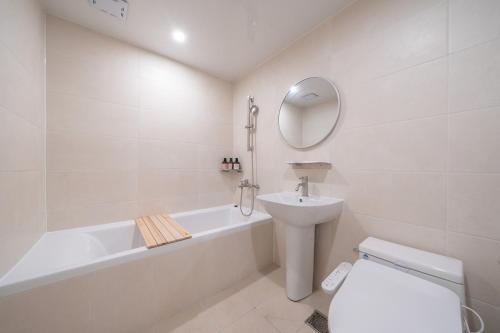 a white bathroom with a sink and a tub and a toilet at Aank Hotel Ilsan in Goyang
