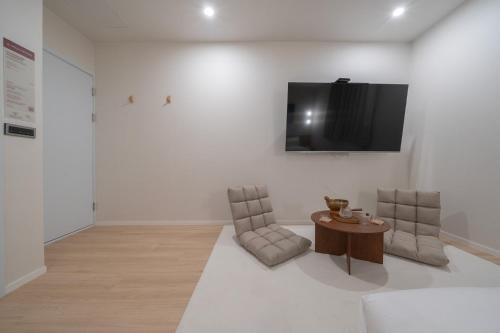 a room with two chairs and a tv on a wall at Aank Hotel Ilsan in Goyang