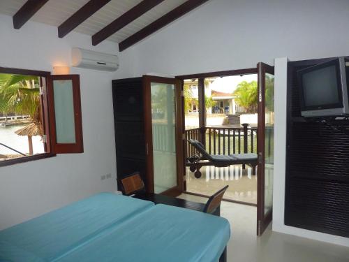 a bedroom with a bed and a tv and a balcony at AquaVilla Bonaire in Kralendijk