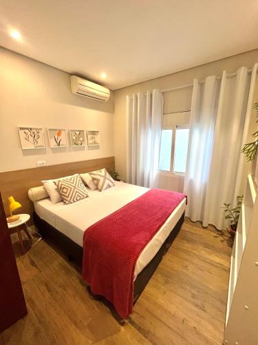 a bedroom with a bed with a red blanket at Casa Cozy - Excelente Localização in Piracicaba