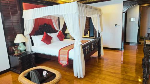 a bedroom with a canopy bed with red pillows at Villa Sirilanna Hotel in Chiang Mai