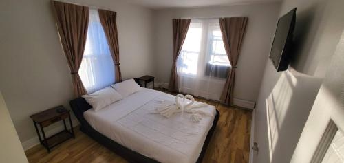 a bedroom with a white bed with two windows at 2 BR Apt|15 Min to NYC|Book Today in North Bergen