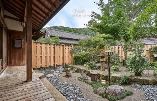 a garden with a wooden walkway next to a fence at Craft Inn WARAKU in Shizuoka