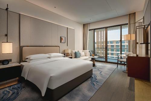 a bedroom with a large white bed and a large window at Hyatt Regency Huangshan Hengjiangwan in Huangshan