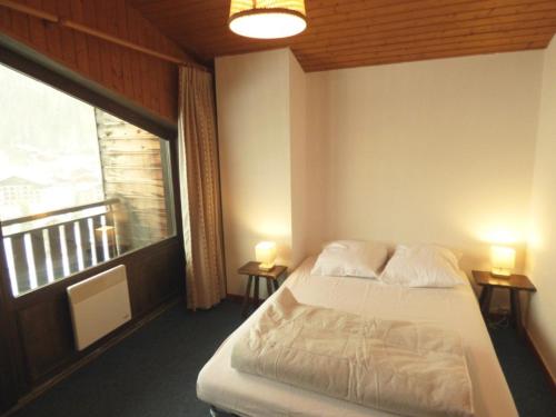 a bedroom with a bed and a large window at Duplex 3 pièces aux pieds des pistes - 8 pers - FR-1-458-250 in Le Chinaillon