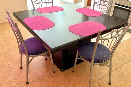 a table with pink and purple cushioned chairs around it at Central - Gated - 2 Bedrooms - Near Beaches in Julianadorp
