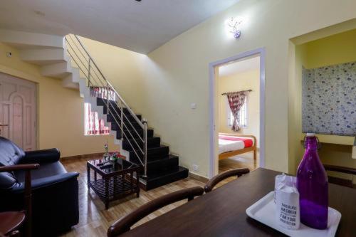 a living room with a table and a staircase at Kodai Mist Starlight Hotels in Kodaikānāl