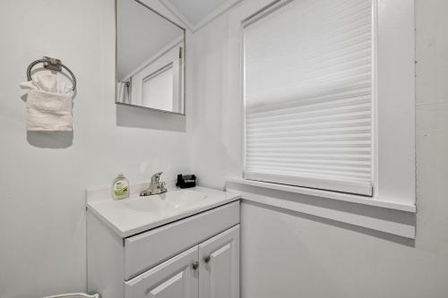 a white bathroom with a sink and a window at Affordable Private Studio in Pensacola