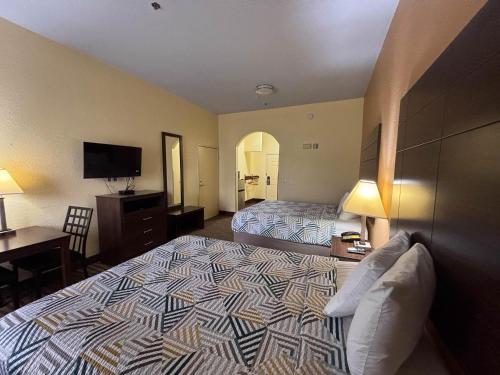 a hotel room with two beds and a desk at Studio 6 Suites Pasadena, TX in Pasadena