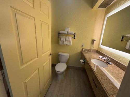 a bathroom with a toilet and a sink and a door at Studio 6 Suites Pasadena, TX in Pasadena