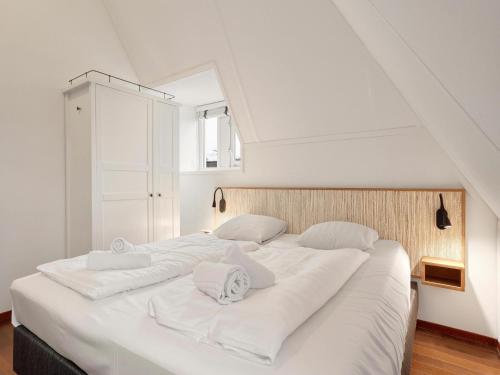 a large white bed with white sheets and pillows at Comfortable Waterfront Park Retreat in Midlaren