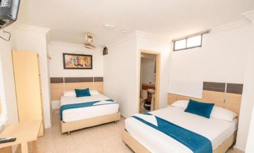 a hotel room with two beds and a desk and a desk at Hotel Caribe Real Inn in Santa Marta