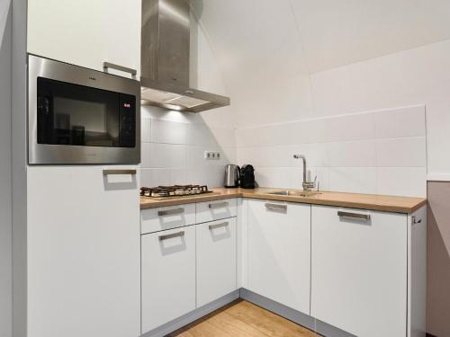 a white kitchen with a sink and a microwave at Lakeside Bungalow with Private Sauna in Midlaren