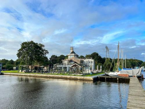 a building next to a river with boats in the water at Lakeside Bungalow with Private Sauna in Midlaren