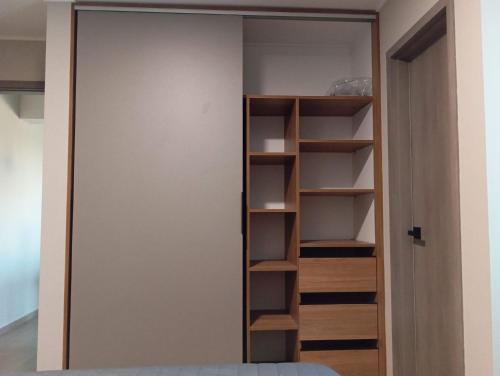 ein Schrank mit Holzregalen und einer Tür in der Unterkunft APARTAMENTO DE LUJO en HERA TOWER in La Playa Bejarano