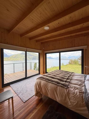 a bedroom with a large bed and large windows at Casa con vistas al Lago Ranco in Futrono