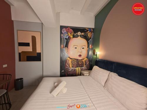 a bed in a room with a painting on the wall at Citizen Hotel in Manila