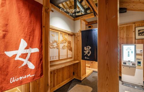 a room with wooden walls and a window with a flag at Craft Inn WARAKU in Shizuoka