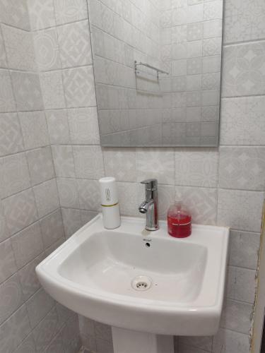 a white sink in a bathroom with a mirror at Home 2 minutes drive to airport in Zanzibar City