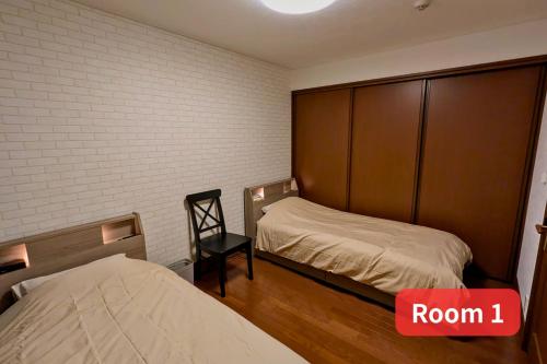 a small room with two beds and a chair at Vacation House 1 in Funabashi