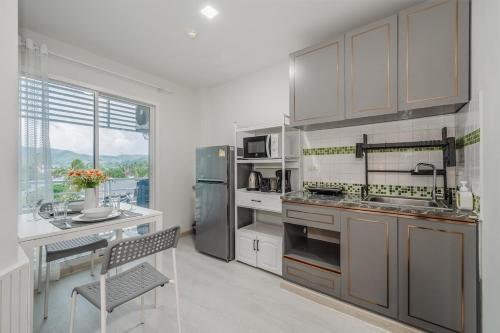 Ban KathuにあるA Stylish Condo in Local Area Kathu, Phuketのキッチン(ステンレス製の電化製品、テーブル付)
