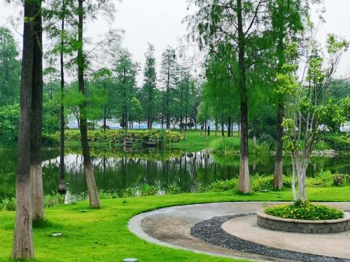 a walkway in a park with trees and a pond at Vignette Collection The Xanadu Guangzhou, an IHG Hotel in Guangzhou