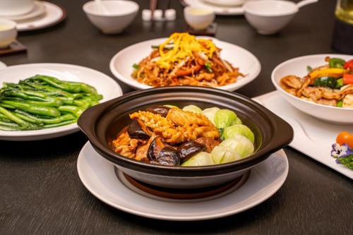 a bowl of food on a table with plates of food at Vignette Collection The Xanadu Guangzhou, an IHG Hotel in Guangzhou