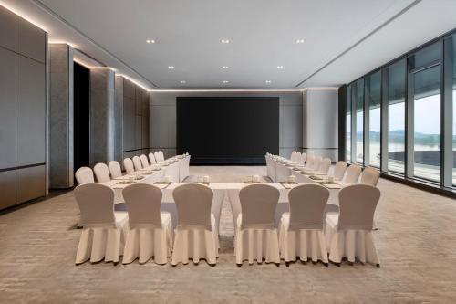 a conference room with a long table and white chairs at Vignette Collection The Xanadu Guangzhou, an IHG Hotel in Guangzhou