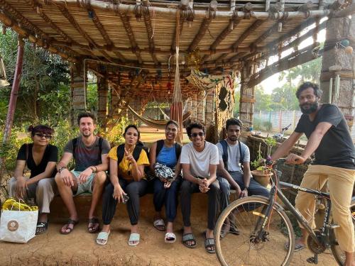 a group of people posing for a picture under a wooden structure at Time Travellers Hostel in Auroville