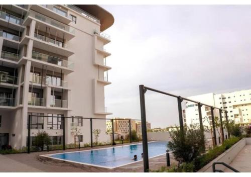 a swimming pool in front of a building at Masdar 2BR Luxury Escape - Pool & Parking in Abu Dhabi