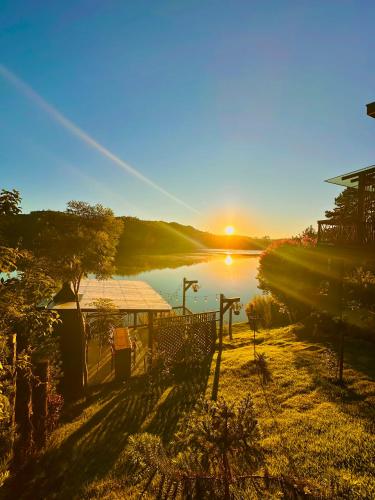 a view of a lake with the sun in the distance at Santuá - Cabana Bellagio in Rio dos Cedros