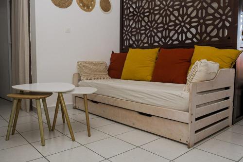 un sofá con almohadas coloridas sentado junto a una mesa en Le Cocon Cayennais - Résidence De Charme, en Cayenne