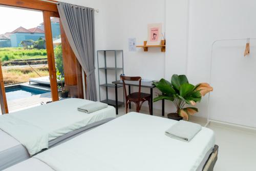two beds in a room with a table and a window at Backyard Canggu in Canggu